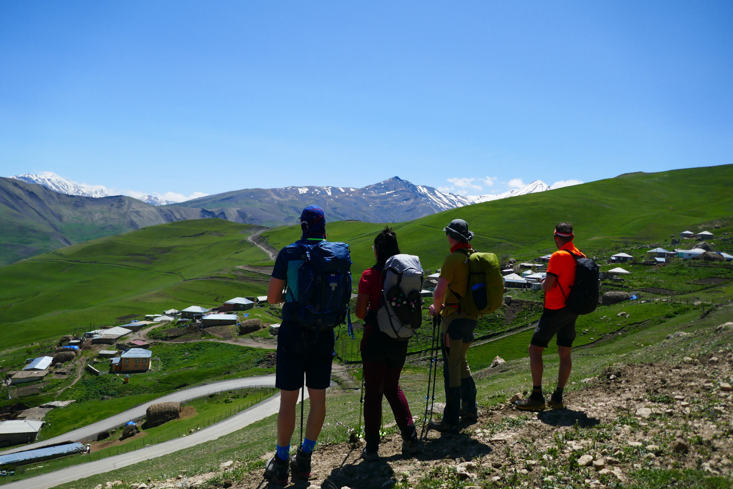 A small group of hikers looking down at Khinalig village and the Greater Caucasus, Azerbaijan