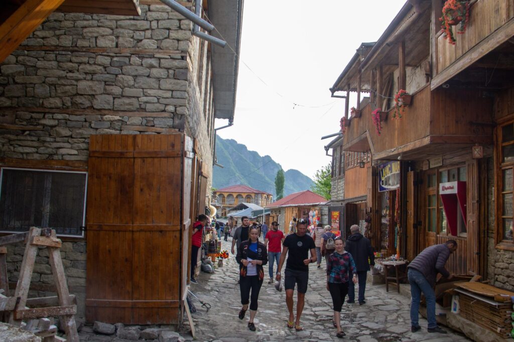 Group walking along the cobbled main street of Lahij village, with stone houses and wooden balconies